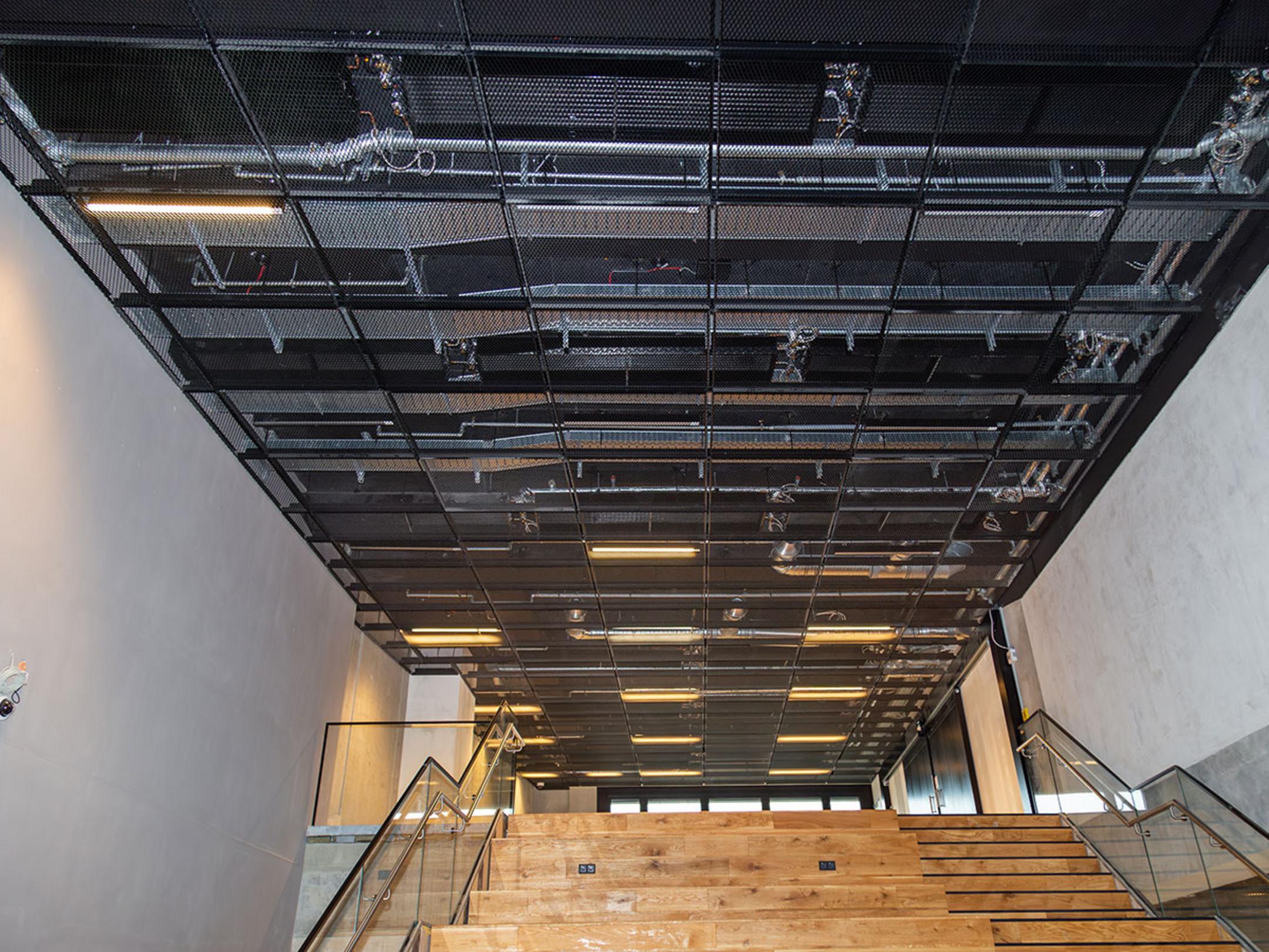 Die offenliegenden Kabeltragsysteme an der Decke im East-Side-Tower, unten eine Treppe.
