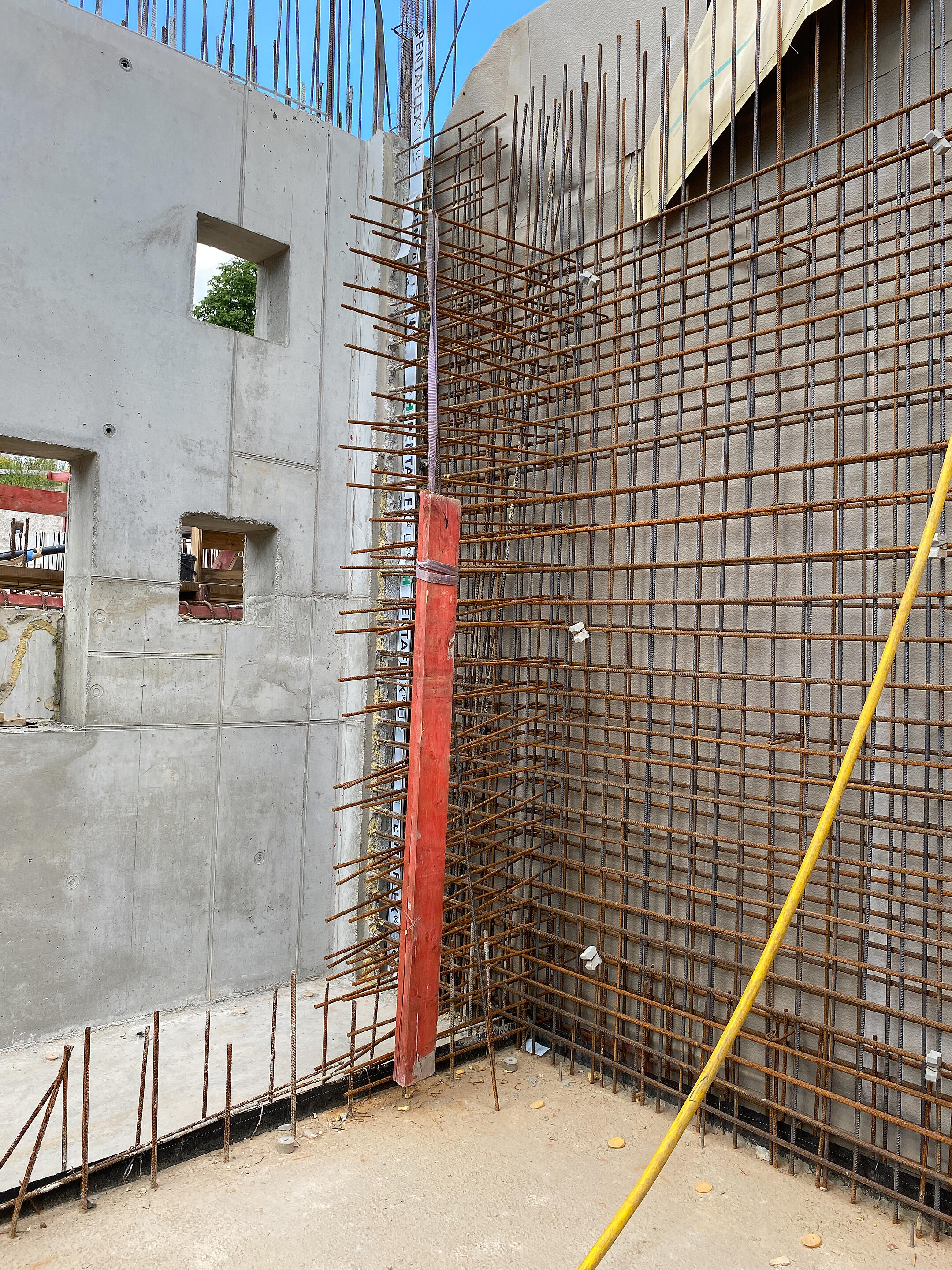 Baustelle mit sichtbaren Bewehrungsstäben und Betonbauteil, im Hintergrund sind Abdichtungselemente PENTAFLEX zu erkennen