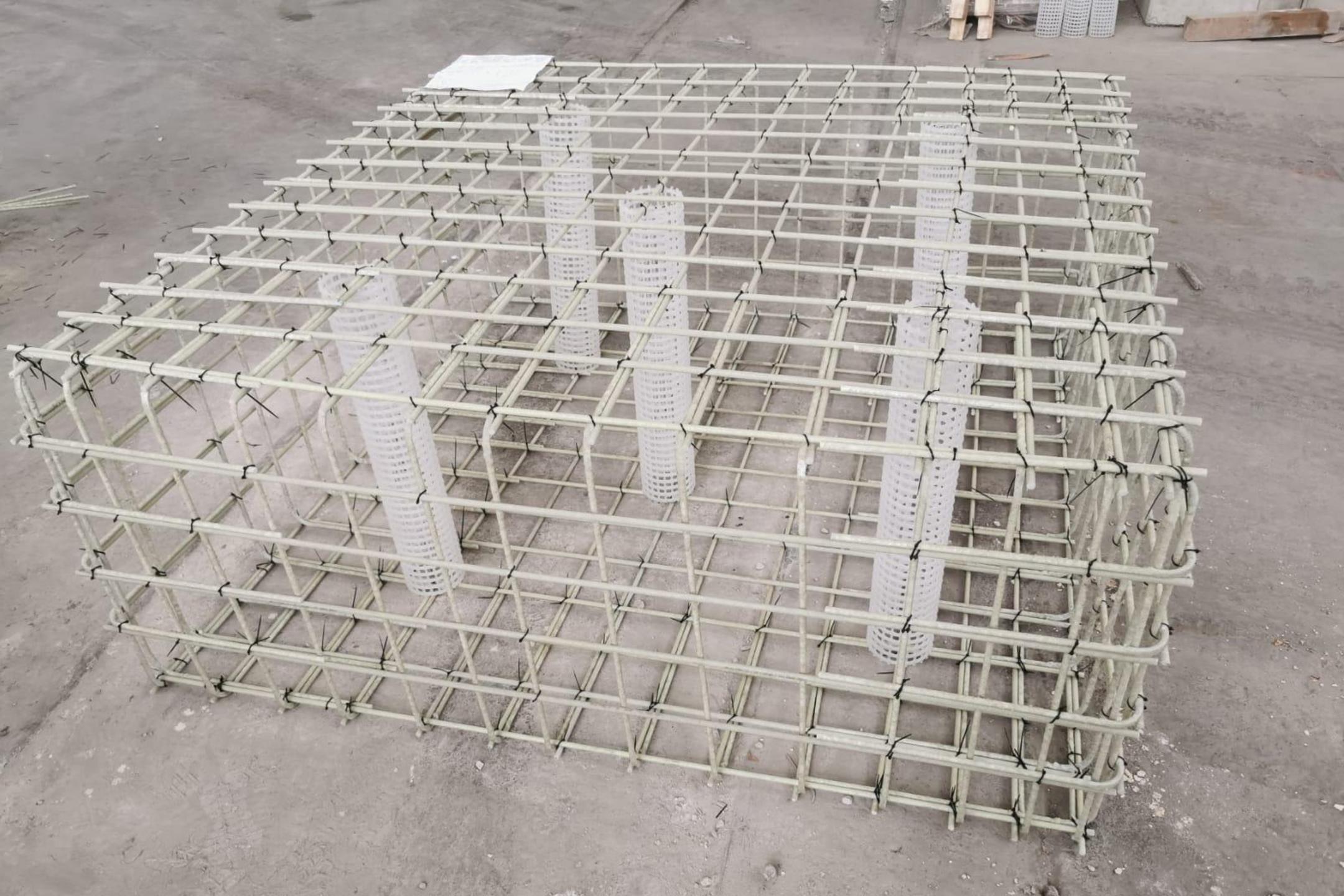 Gitterstruktur aus Glasfaserkunststoffbewehrungsstäben mit 5 Kunststoffzylindern auf einer Betonfläche liegend