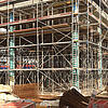 Blick auf eine Baustelle und Baugerüste, mit Materialien und Werkzeugen im Vordergrund.