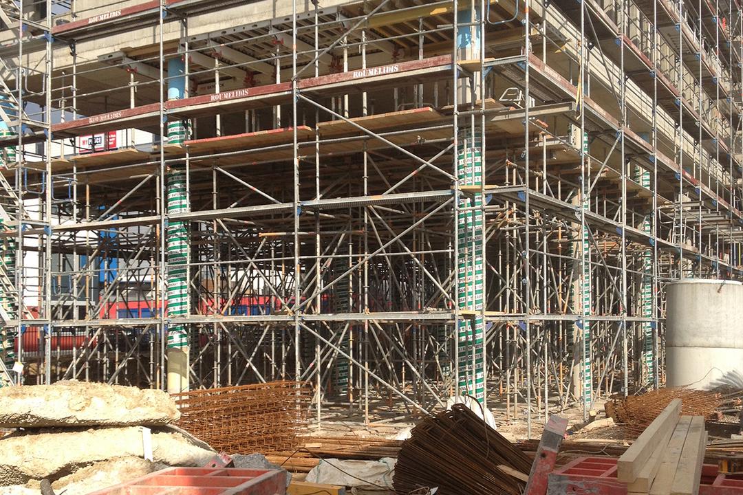 Blick auf eine Baustelle und Baugerüste, mit Materialien und Werkzeugen im Vordergrund.