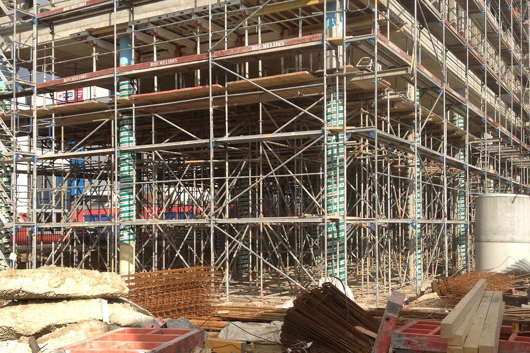 Blick auf eine Baustelle und Baugerüste, mit Materialien und Werkzeugen im Vordergrund.