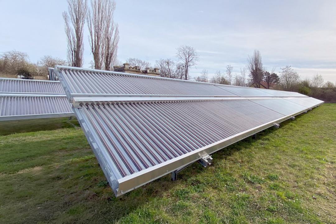 Solarthermie-Freiflächenanlage mit Vakuumröhrenkollektoren auf verzinkter Stahlunterkonstruktion in schräger Aufstellung auf grüner Wiese
