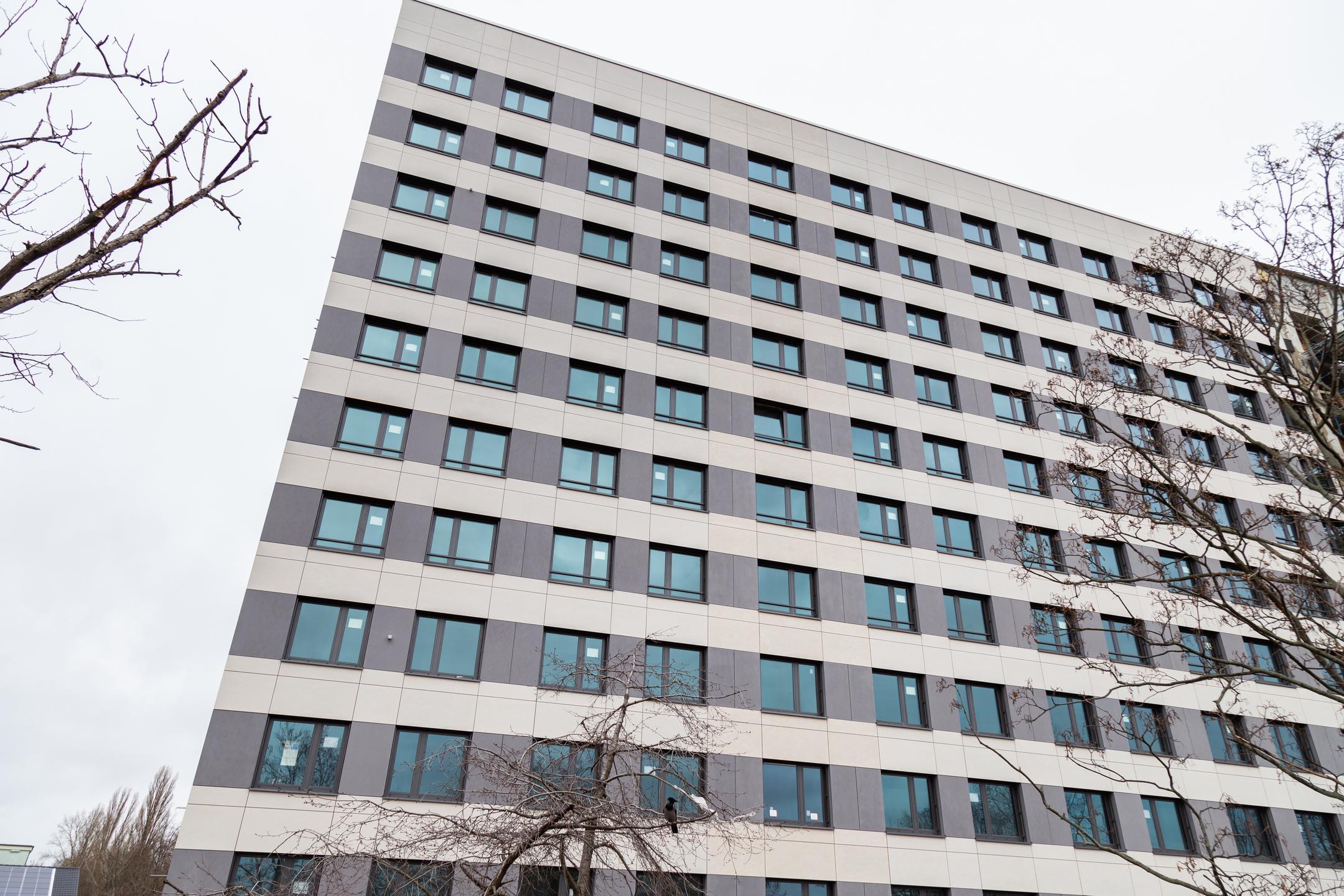 Moderne Fassade eines mehrstöckigen Bürogebäudes mit vielen Fenstern und kahlen Bäumen im Vordergrund