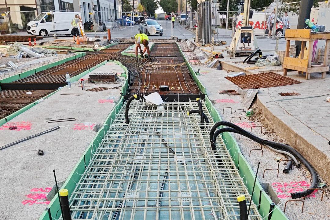 Bewehrungsstäbe aus Glasfaserkunststoff, eingelassen in den Boden auf einer Baustelle, im Hintergrund sind Gebäude zu erkennen