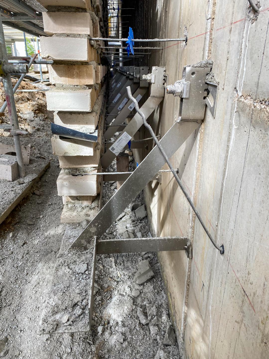 Blick zwischen Vorhangfassade und Betonwand mit Verblenderkonsolen