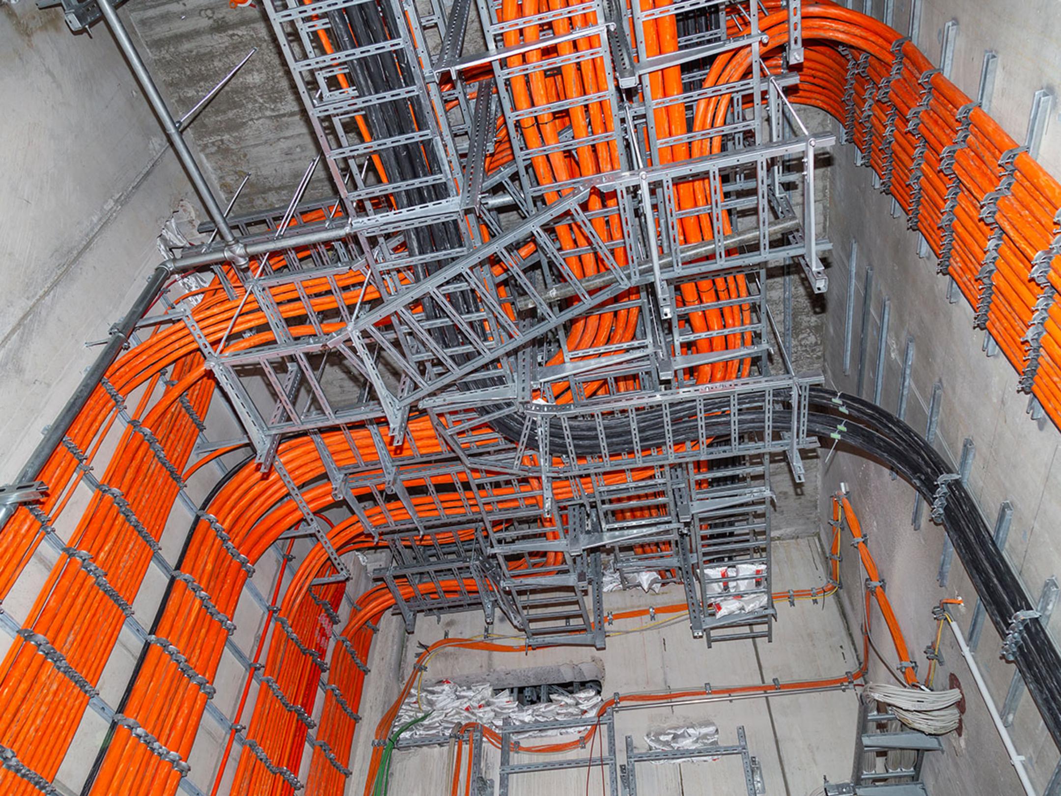 Dicke, leuchtend orange Kabel verlaufen im Gebäudeinneren durch Kabelführungsschienen.