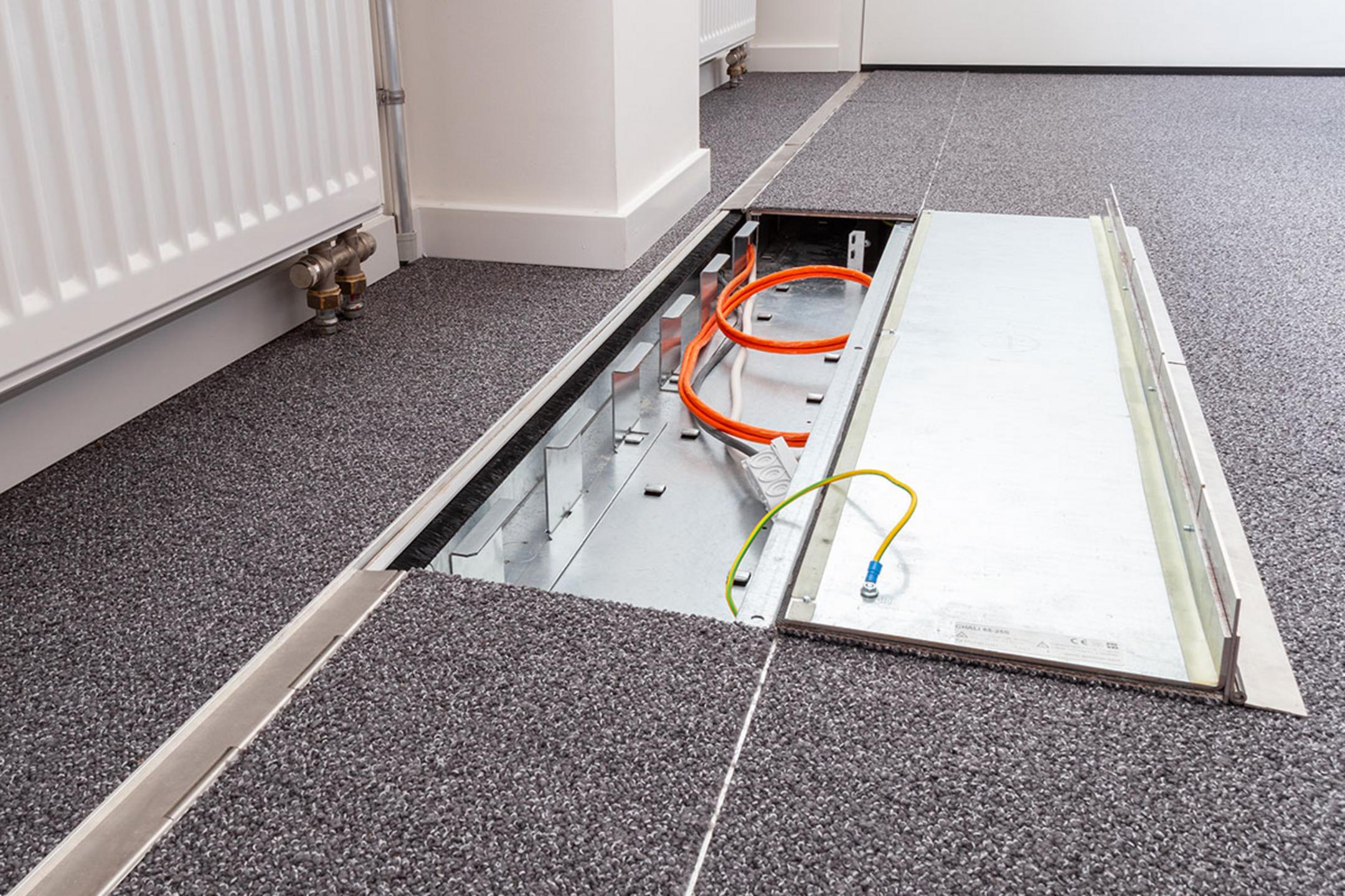 Das in den Boden eingelassene Kanalsystem für Kabel, halb aufgeklappt, in einem Büro.