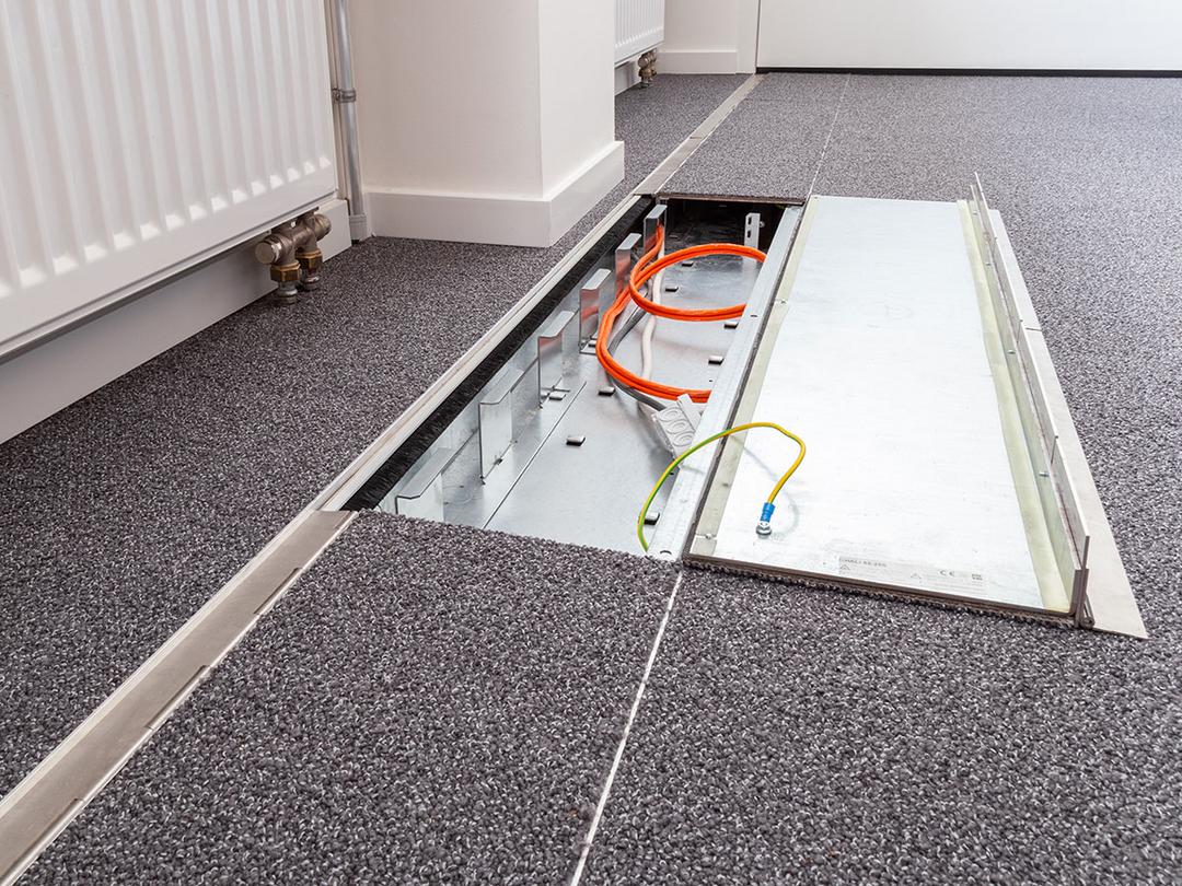 Das in den Boden eingelassene Kanalsystem für Kabel, halb aufgeklappt, in einem Büro.