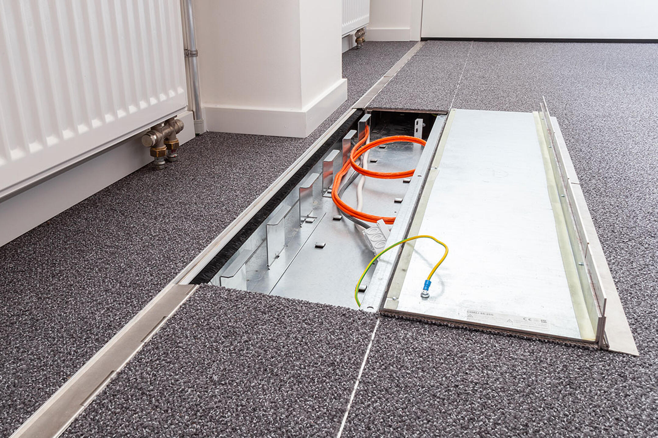 Das in den Boden eingelassene Kanalsystem für Kabel, halb aufgeklappt, in einem Büro.