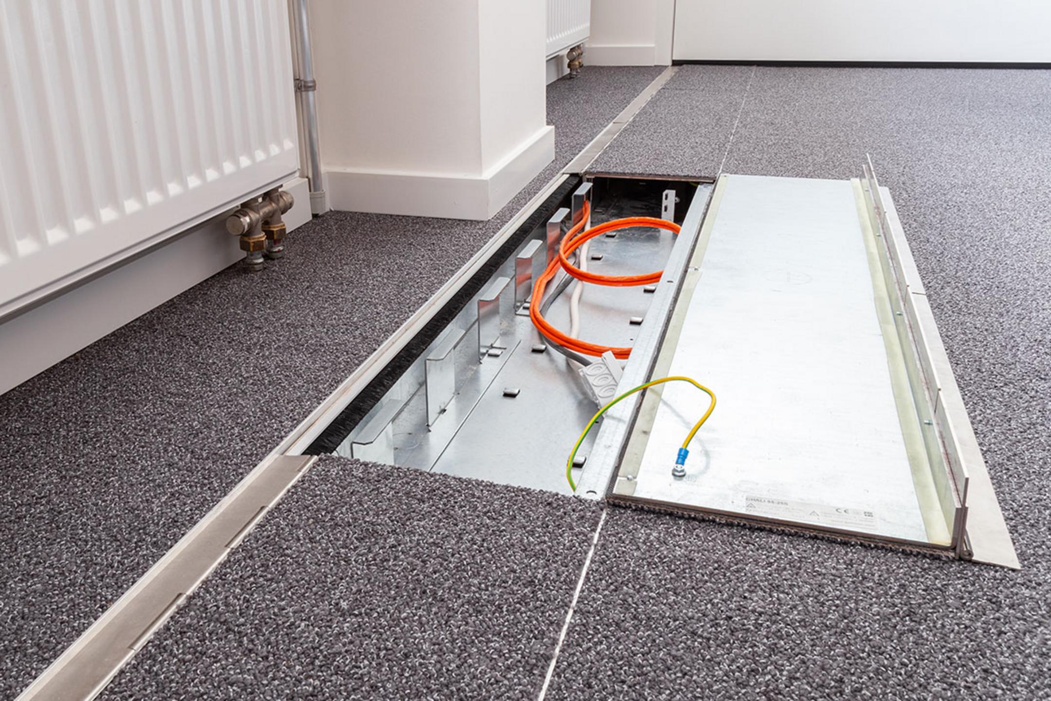 Das in den Boden eingelassene Kanalsystem für Kabel, halb aufgeklappt, in einem Büro.