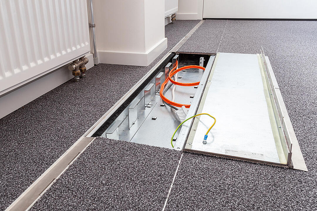 Das in den Boden eingelassene Kanalsystem für Kabel, halb aufgeklappt, in einem Büro.