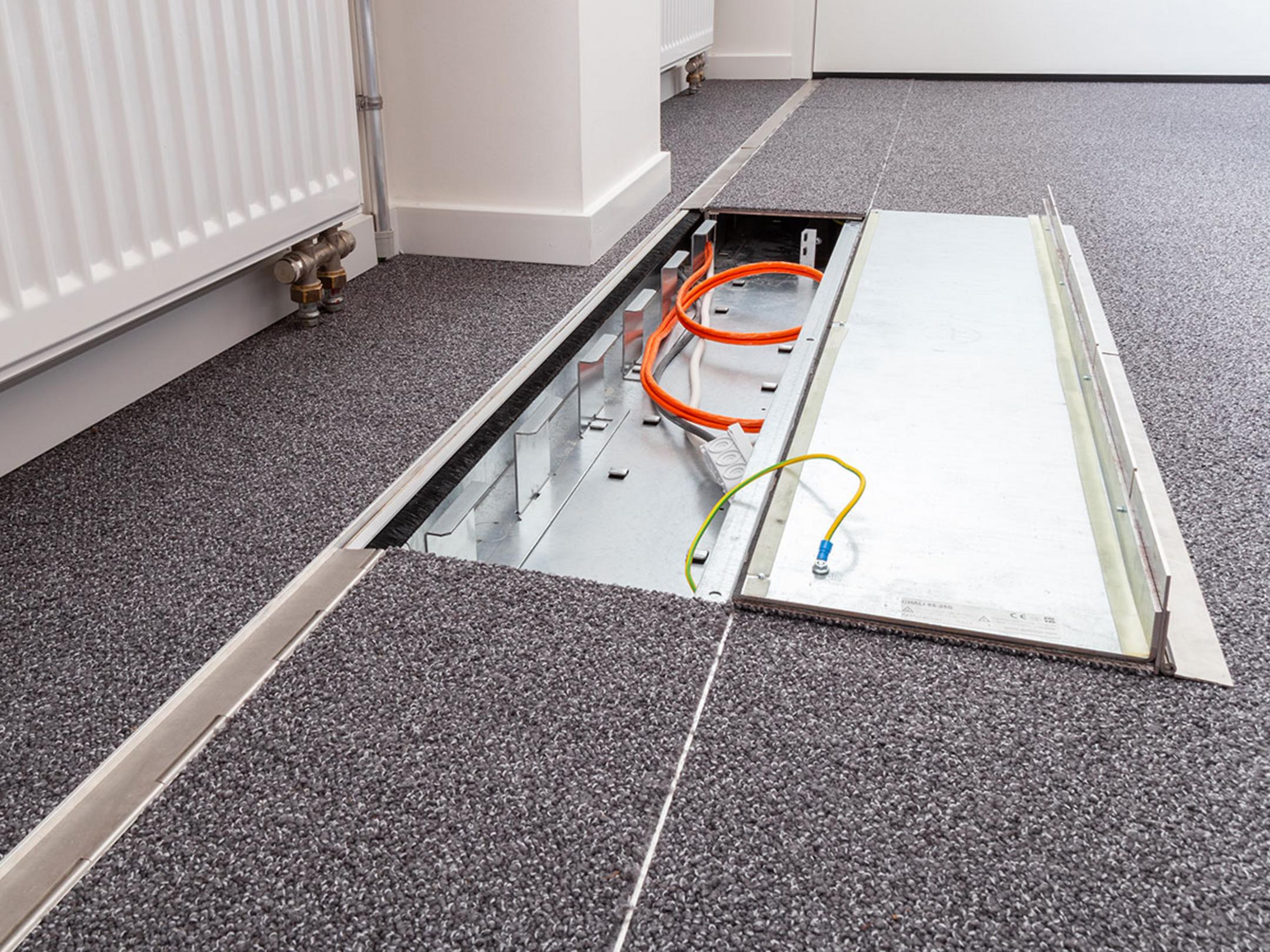 Das in den Boden eingelassene Kanalsystem für Kabel, halb aufgeklappt, in einem Büro.