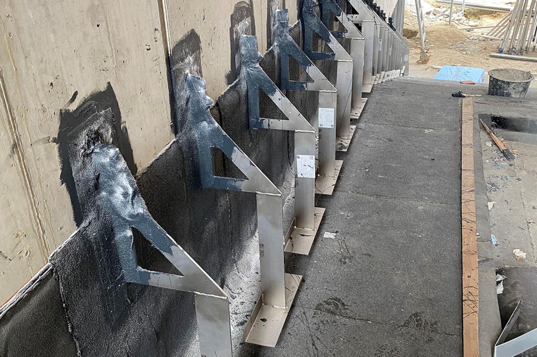 Reihe aus Verblenderkonsolen an einer Wand auf einer Baustelle mit Baumaterialien im Hintergrund