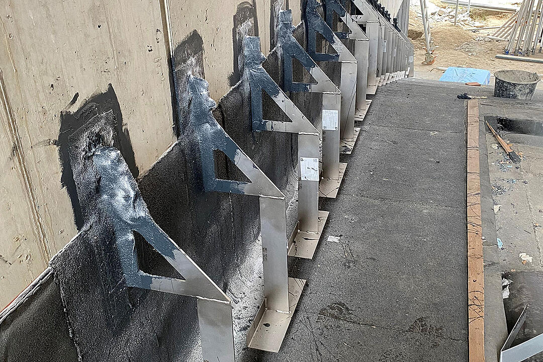 Reihe aus Verblenderkonsolen an einer Wand auf einer Baustelle mit Baumaterialien im Hintergrund