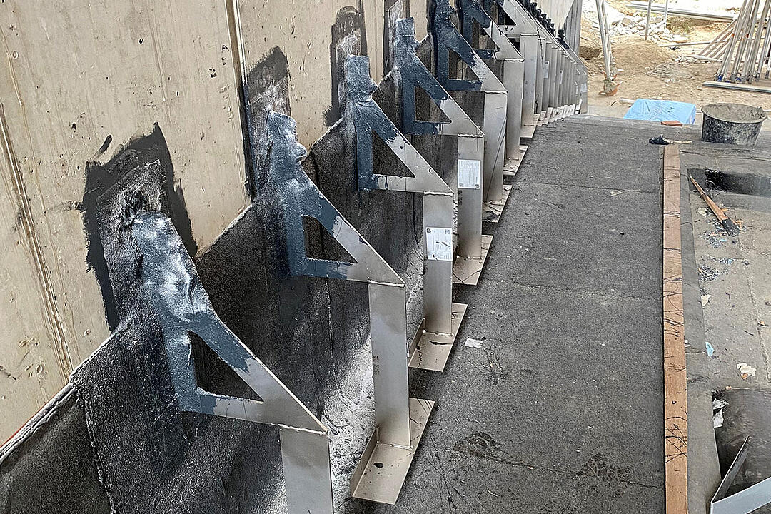 Reihe aus Verblenderkonsolen an einer Wand auf einer Baustelle mit Baumaterialien im Hintergrund