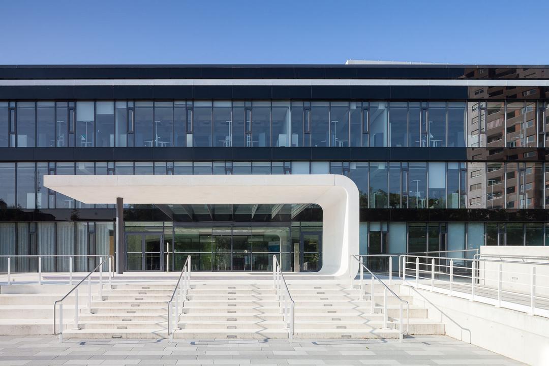 Blick aufs verglaste, moderne Haupthaus des BGV (Badischer GemeindeVersicherungsVerband) in Karlsruhe, darüber blauer Himmel.