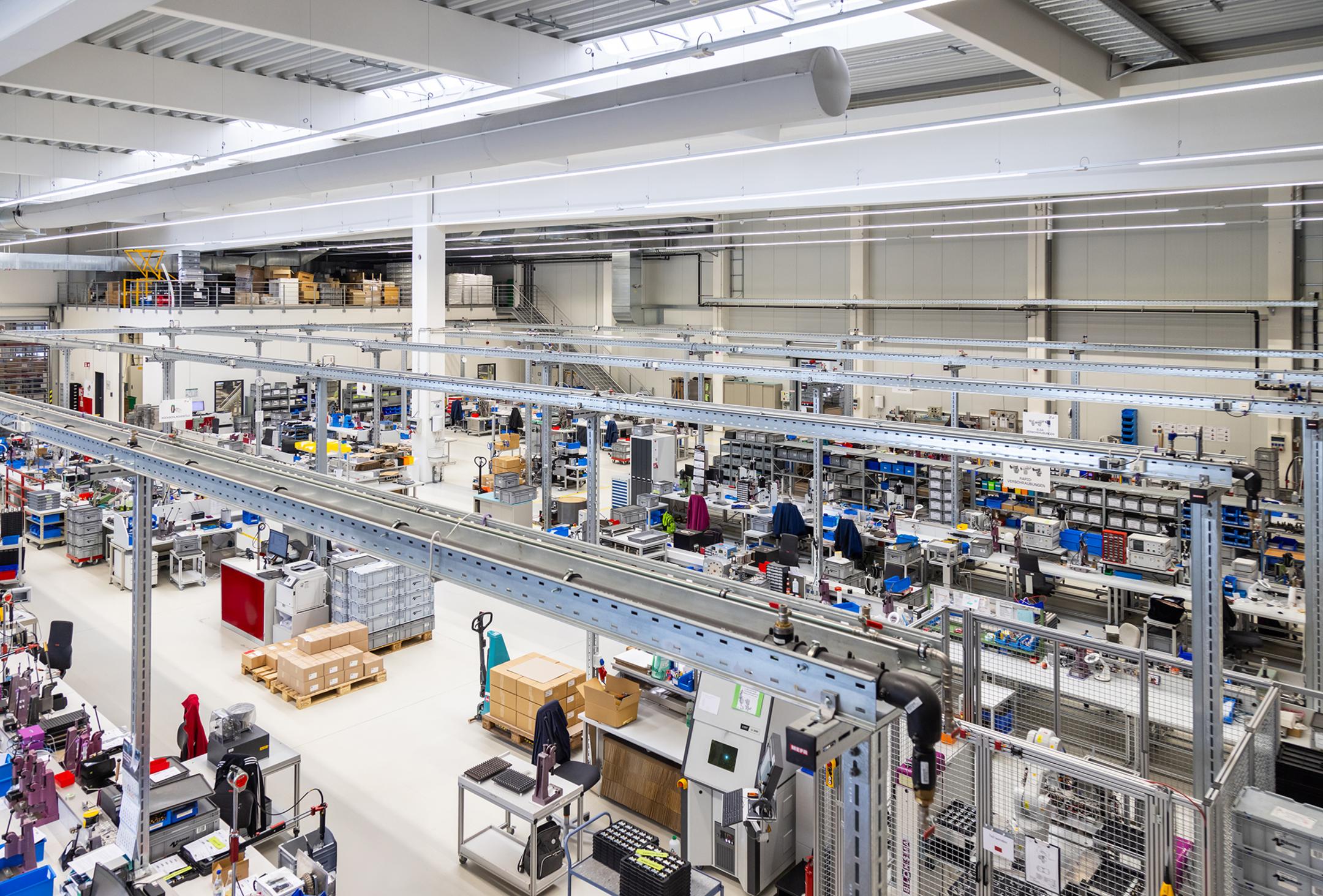 Moderne Produktionshalle mit mehreren Arbeitsplätzen. Im Zentrum des Bildes sieht man Kabeltragsysteme .