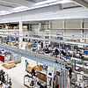 Moderne Produktionshalle mit mehreren Arbeitsplätzen. Im Zentrum des Bildes sieht man Kabeltragsysteme .