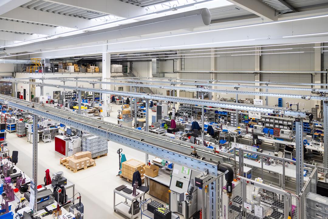 Moderne Produktionshalle mit mehreren Arbeitsplätzen. Im Zentrum des Bildes sieht man Kabeltragsysteme .