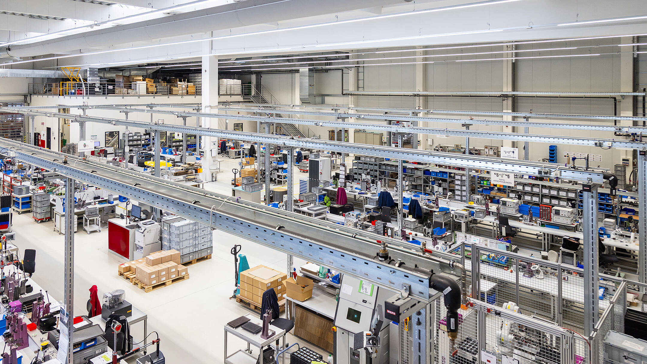 Moderne Produktionshalle mit mehreren Arbeitsplätzen. Im Zentrum des Bildes sieht man Kabeltragsysteme .