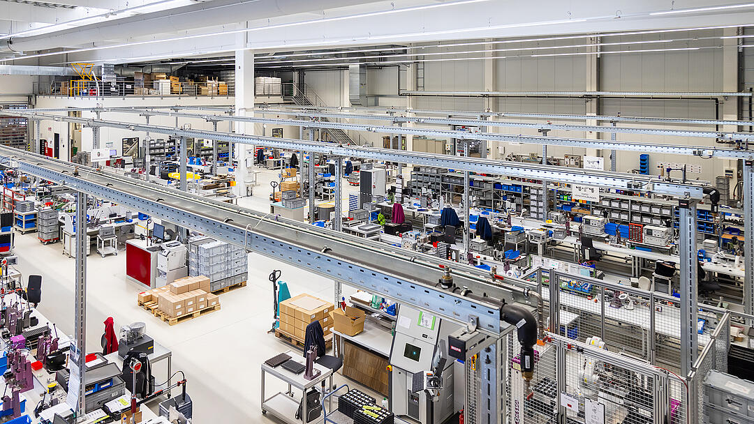 Moderne Produktionshalle mit mehreren Arbeitsplätzen. Im Zentrum des Bildes sieht man Kabeltragsysteme .