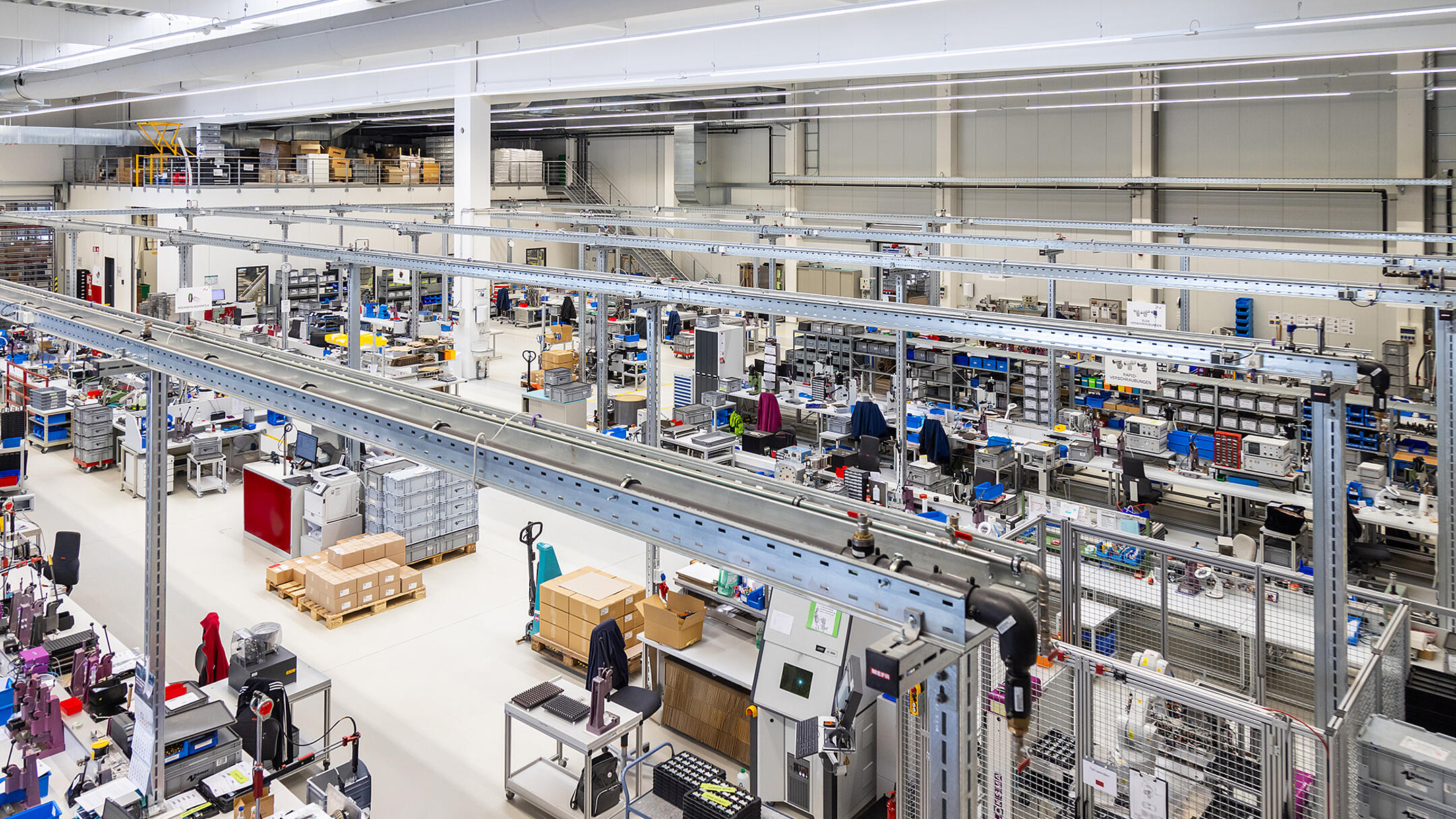 Moderne Produktionshalle mit mehreren Arbeitsplätzen. Im Zentrum des Bildes sieht man Kabeltragsysteme .