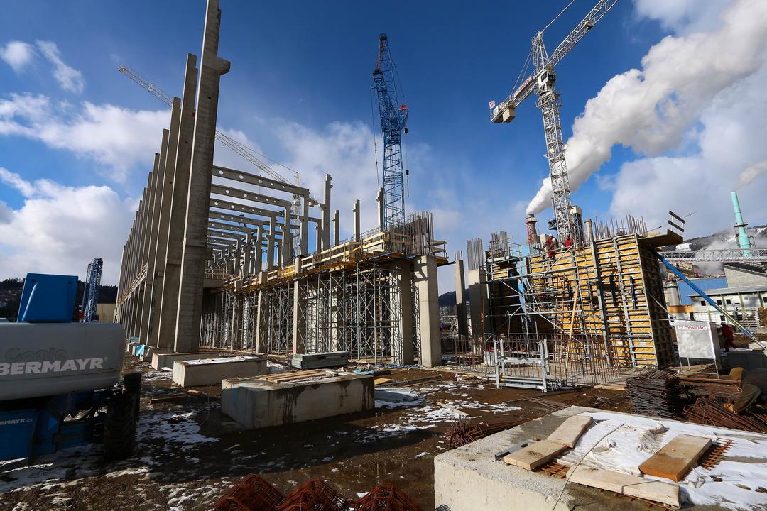 Baustelle mit Kränen, Gerüsten, Betonträgern und Schnee am Boden