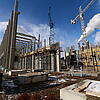 Baustelle mit Kränen, Gerüsten, Betonträgern und Schnee am Boden