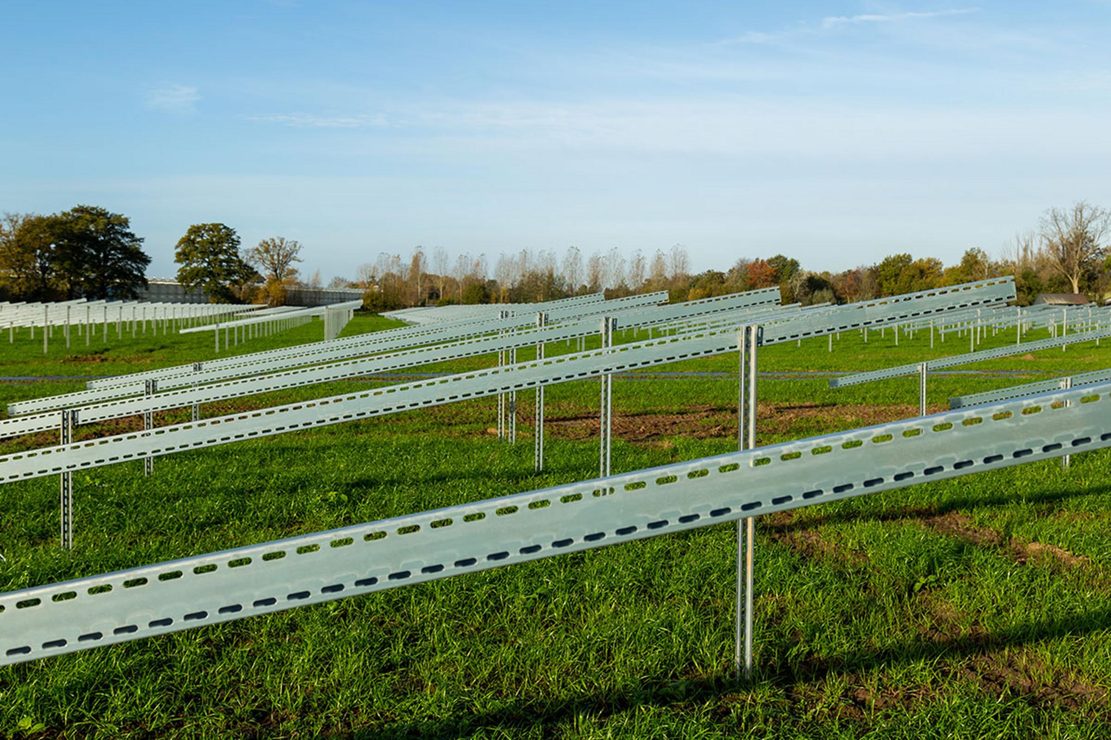 Die Unterkonstruktionen für Solarpanele auf einer grünen Wiese mit blauem Himmel