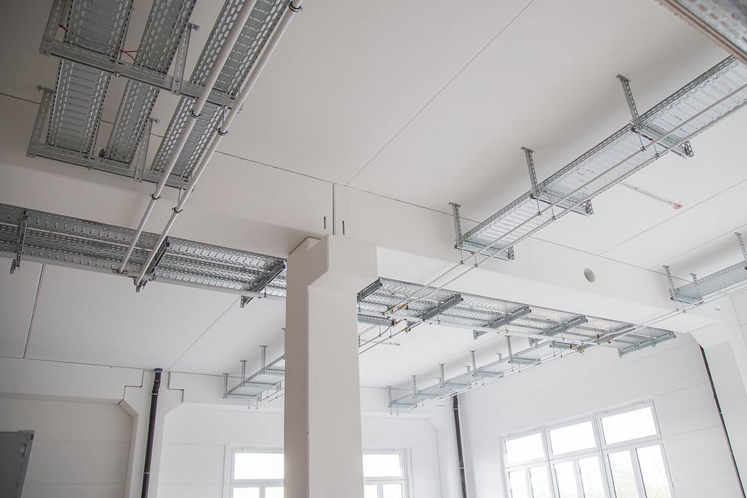 Die Kabeltragsysteme an der Decke des Erweiterungsbaus aus einer anderen Perspektive, in einem lichtdurchfluteten Raum..