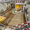 Draufsicht auf Baustelle mit Glasfaserkunststoffbewehrungsstäben umgeben von Absperrungen und Aushub