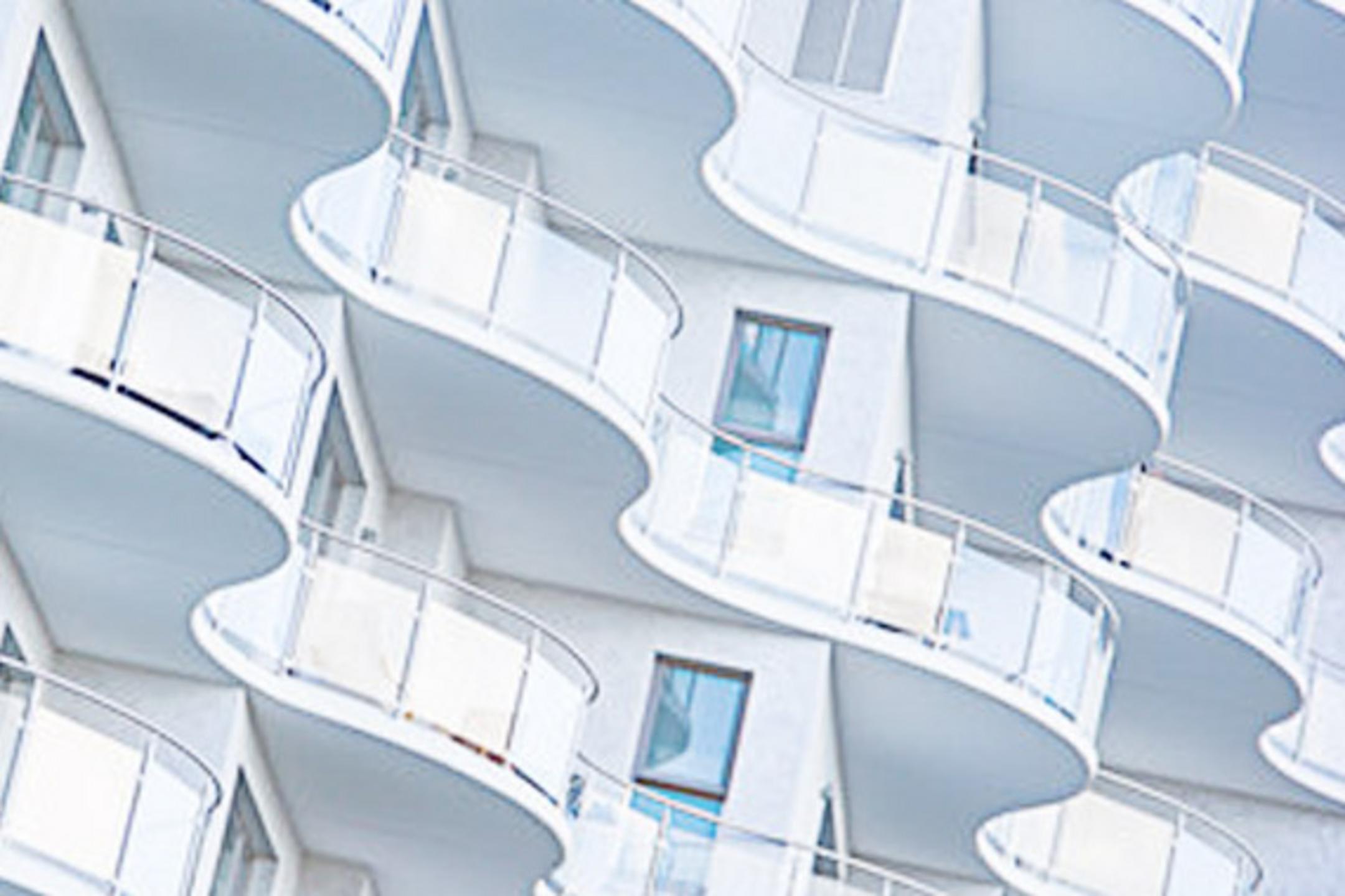 Detailansicht der weißen geschwungenen Fassade mit Glasbalkonen