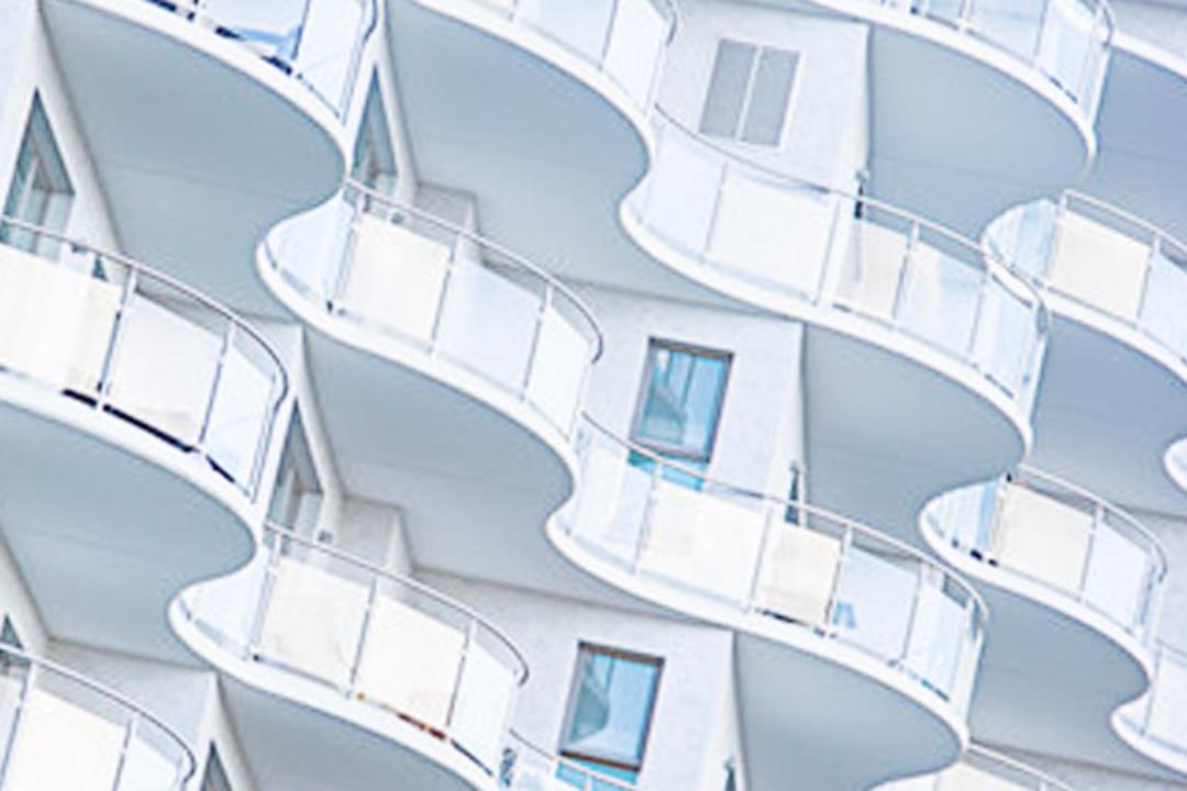 Detailansicht der weißen geschwungenen Fassade mit Glasbalkonen