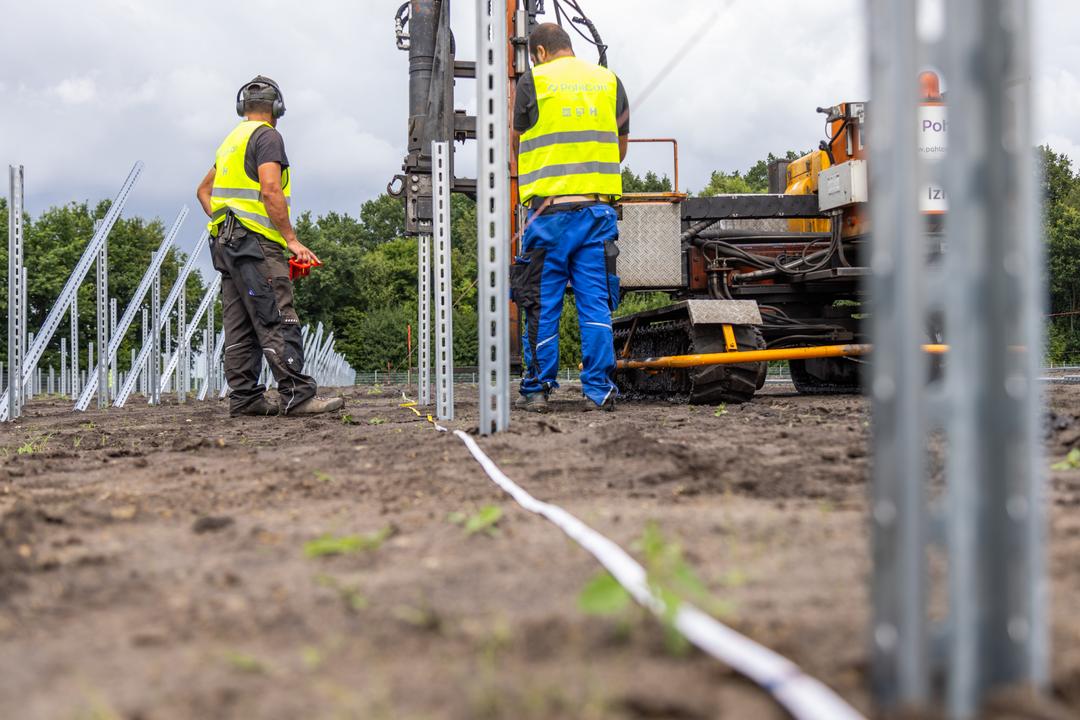 Nahaufnahme von Bauarbeitern beim Setzen von Fundamenten mithilfe eines Baufahrzeugs.