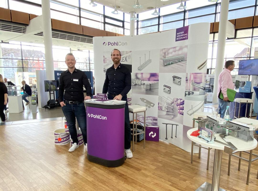 Messestand mit Schriftzug PohlCon und 2 Mitarbeitern sowie Ausstellungsstücken
