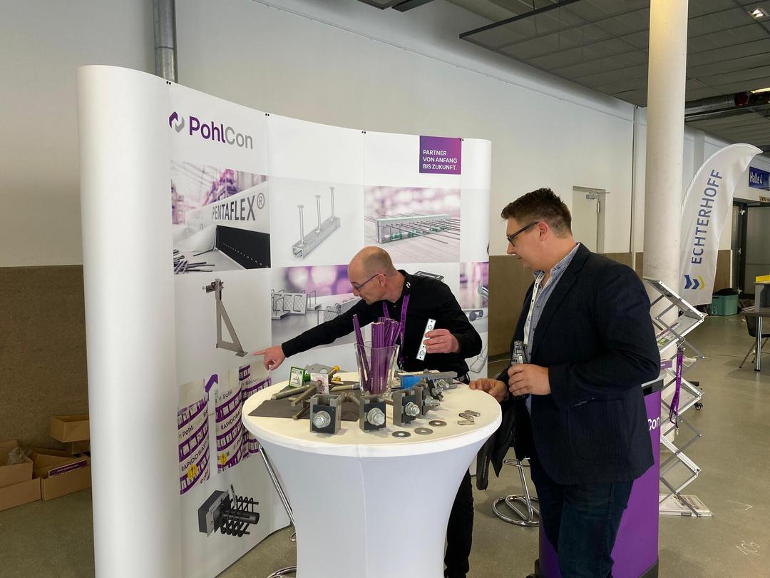 Messestand mit Schriftzug PohlCon, Mitarbeiter und Besucher sowie Ausstellungsstücken