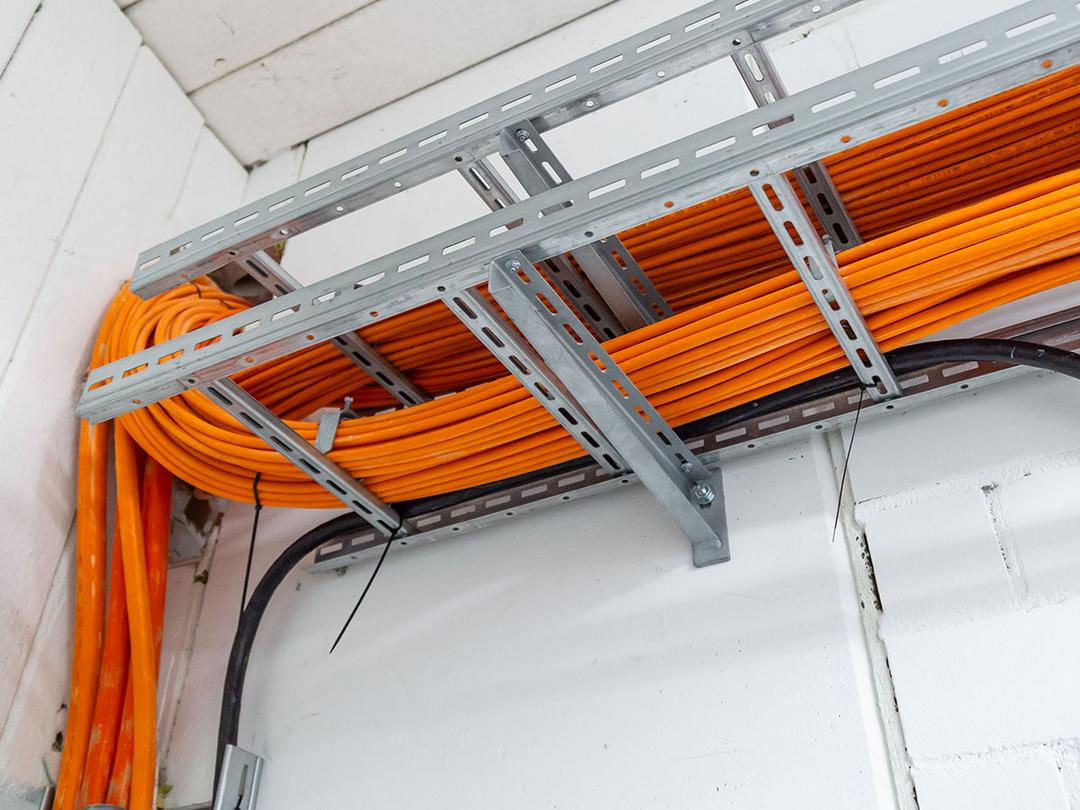Leuchtend orange Kabel, die von Kabeltragsystemen gehalten werden.