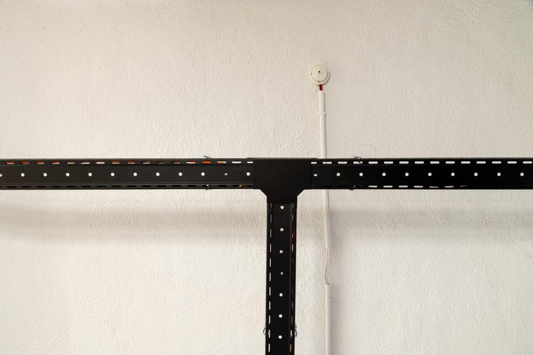 Detailansicht einer T-Kreuzung von schwarzen Kabelrinnen. die an der Decke abgehängt sind.