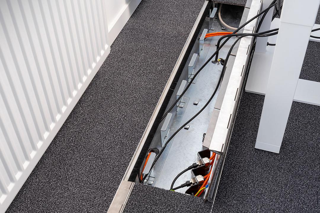 Das in den Boden eingelassene Kanalsystem für Kabel, aufgeklappt, in einem Büro.