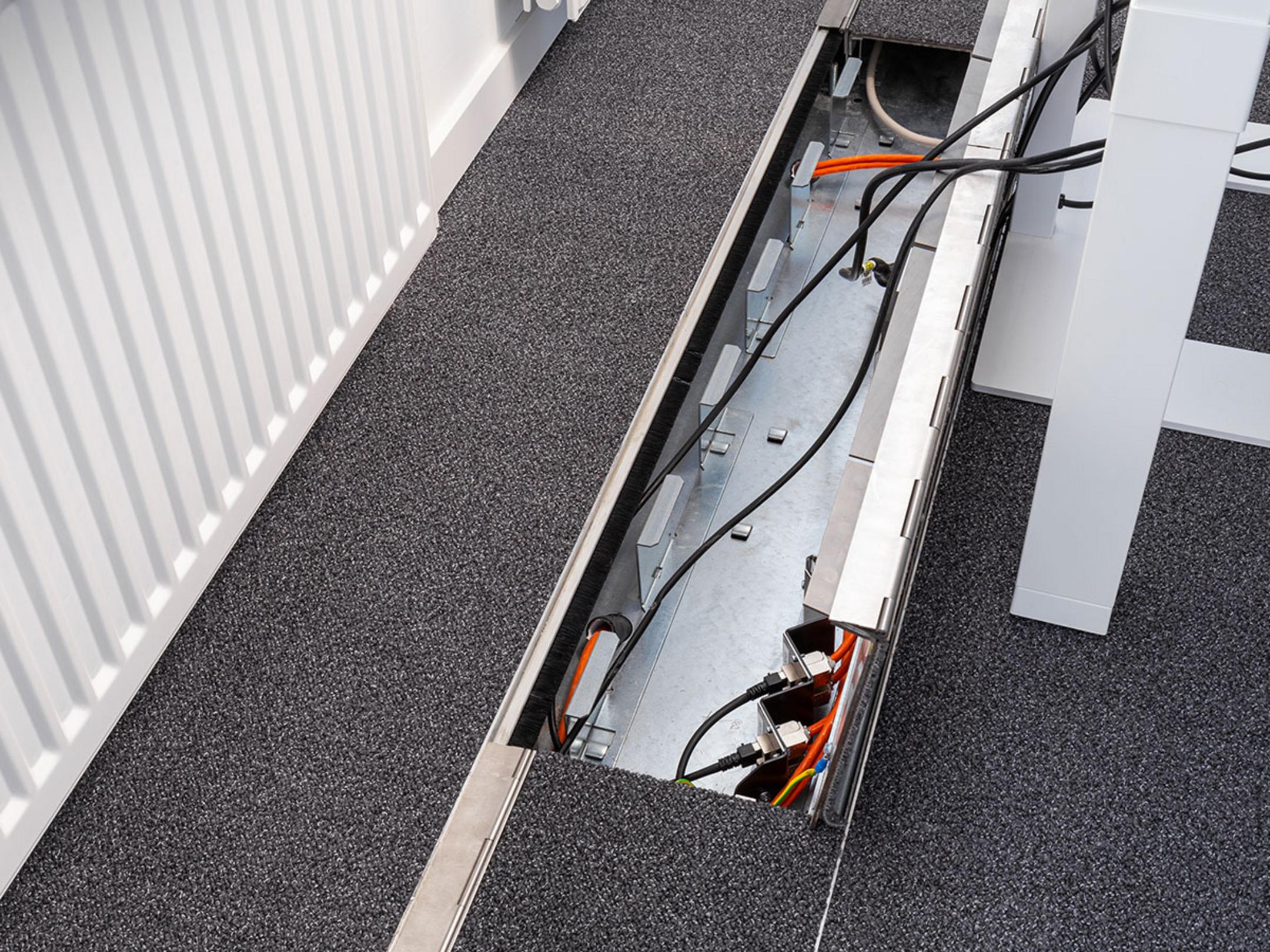 Das in den Boden eingelassene Kanalsystem für Kabel, aufgeklappt, in einem Büro.