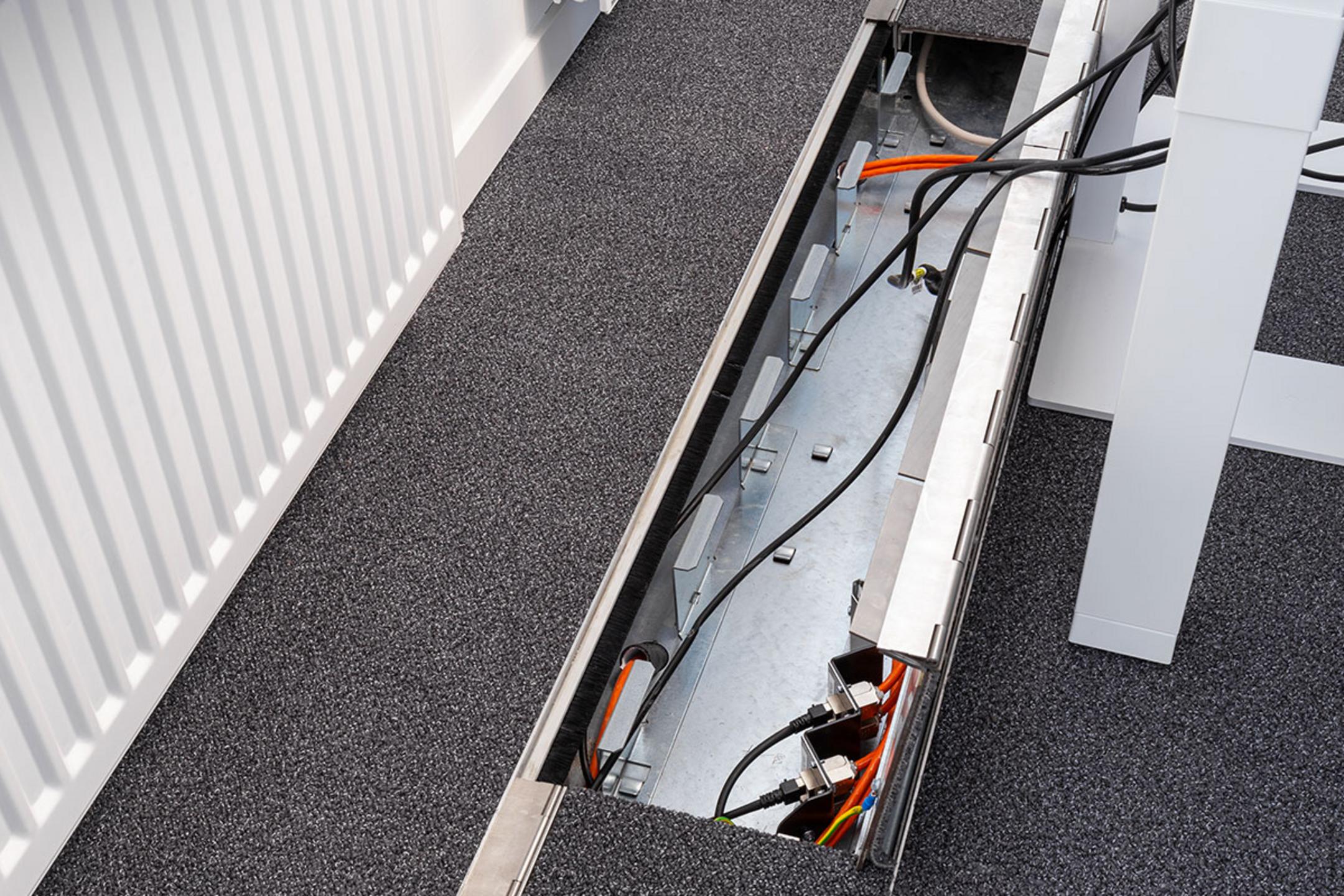 Das in den Boden eingelassene Kanalsystem für Kabel, aufgeklappt, in einem Büro.