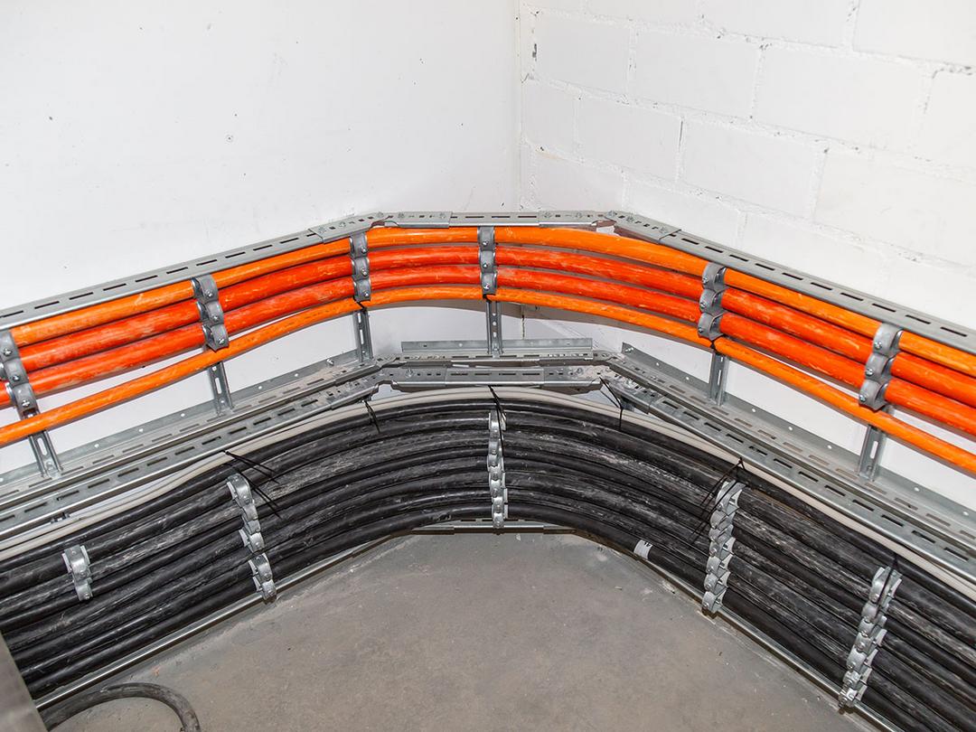 Leuchtend orange Kabel, die von Kabeltragsystemen gehalten werden, an einer anderen Stelle im Gebäude.