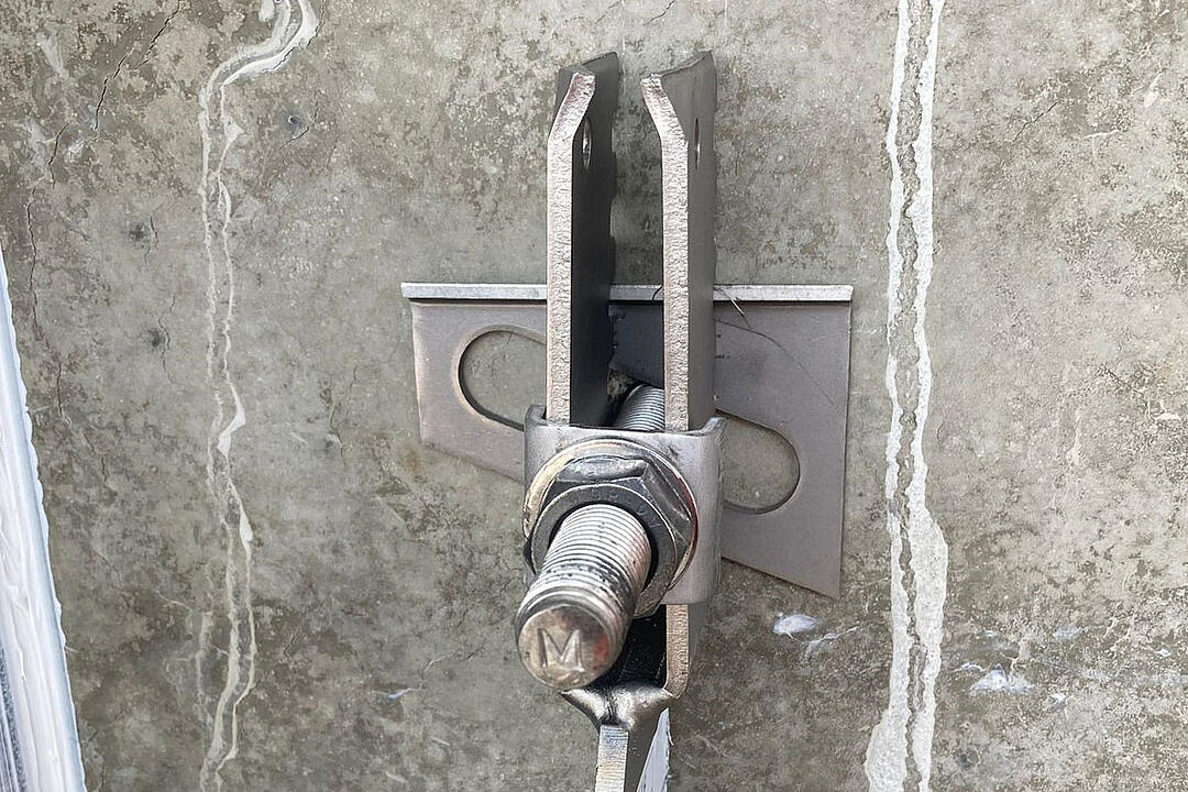 Detailansicht einer Verblenderkonsole mit Schraube und Mutter an einer Betonwand