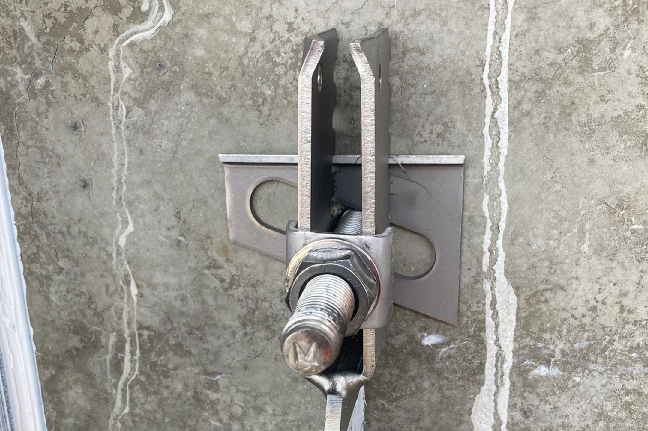 Detailansicht einer Verblenderkonsole mit Schraube und Mutter an einer Betonwand