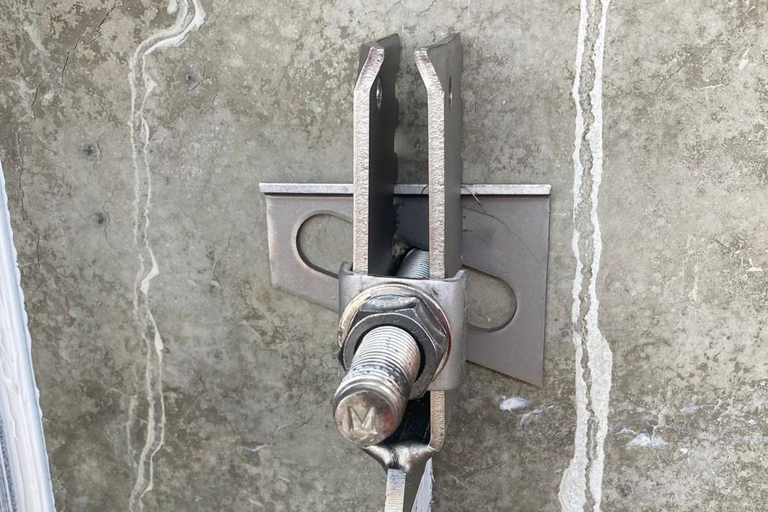 Detailansicht einer Verblenderkonsole mit Schraube und Mutter an einer Betonwand