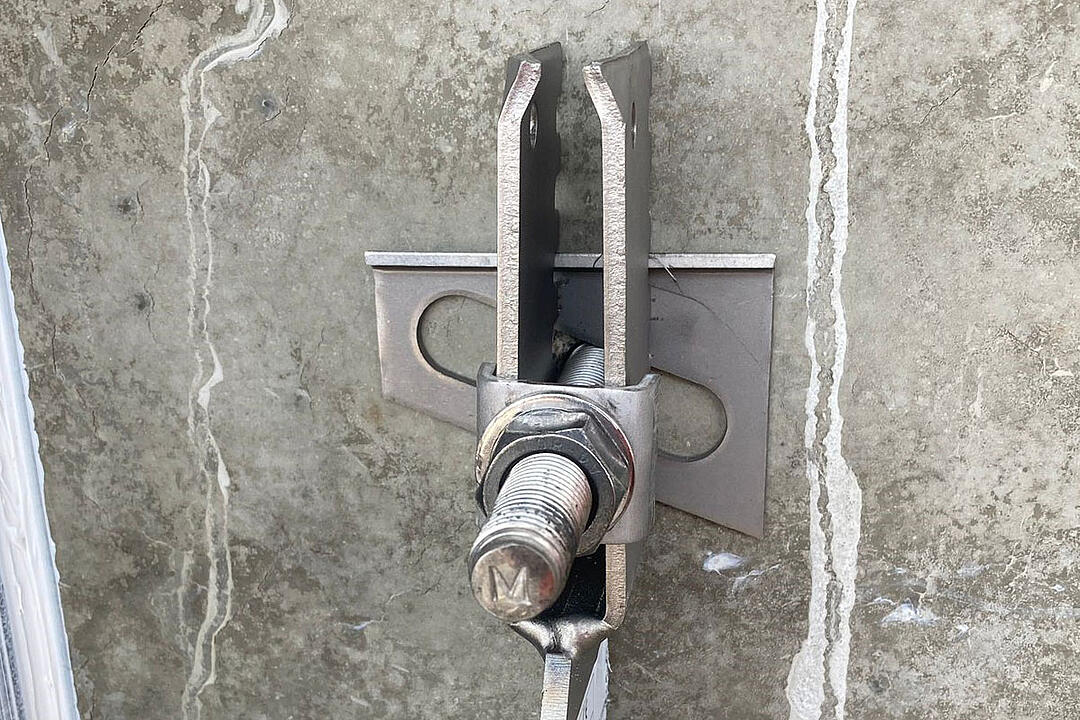 Detailansicht einer Verblenderkonsole mit Schraube und Mutter an einer Betonwand
