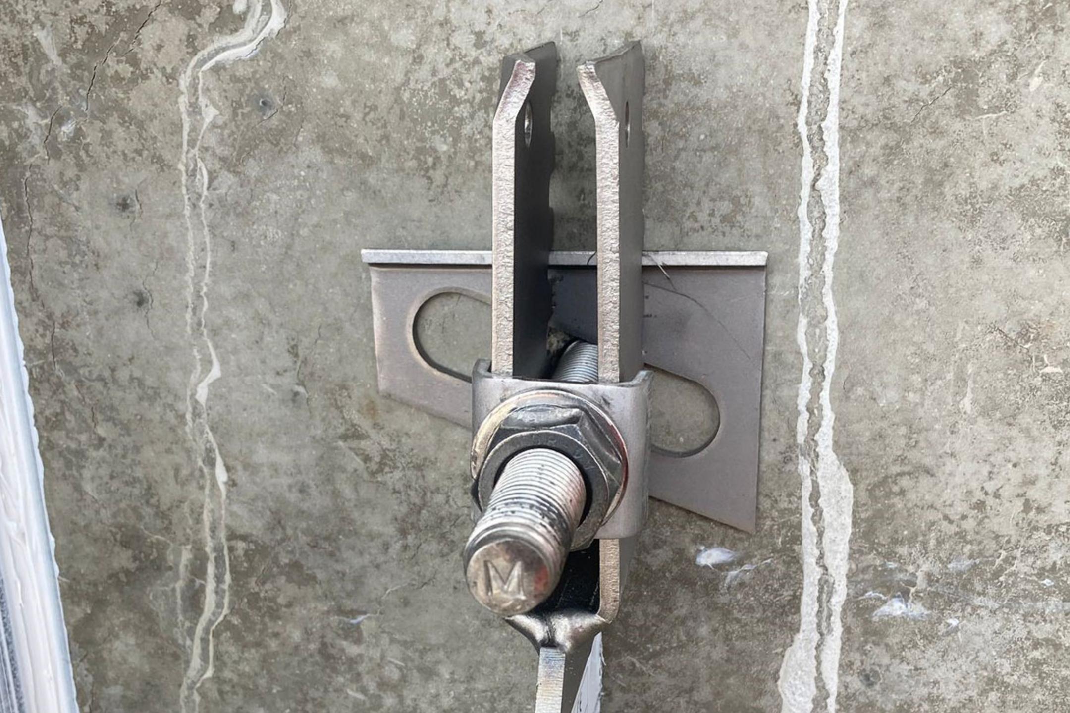 Detailansicht einer Verblenderkonsole mit Schraube und Mutter an einer Betonwand