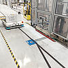 Automatisierter Transportroboter auf einem markierten Industrieboden mit induktiver Ladeeinbaueinheit im Boden