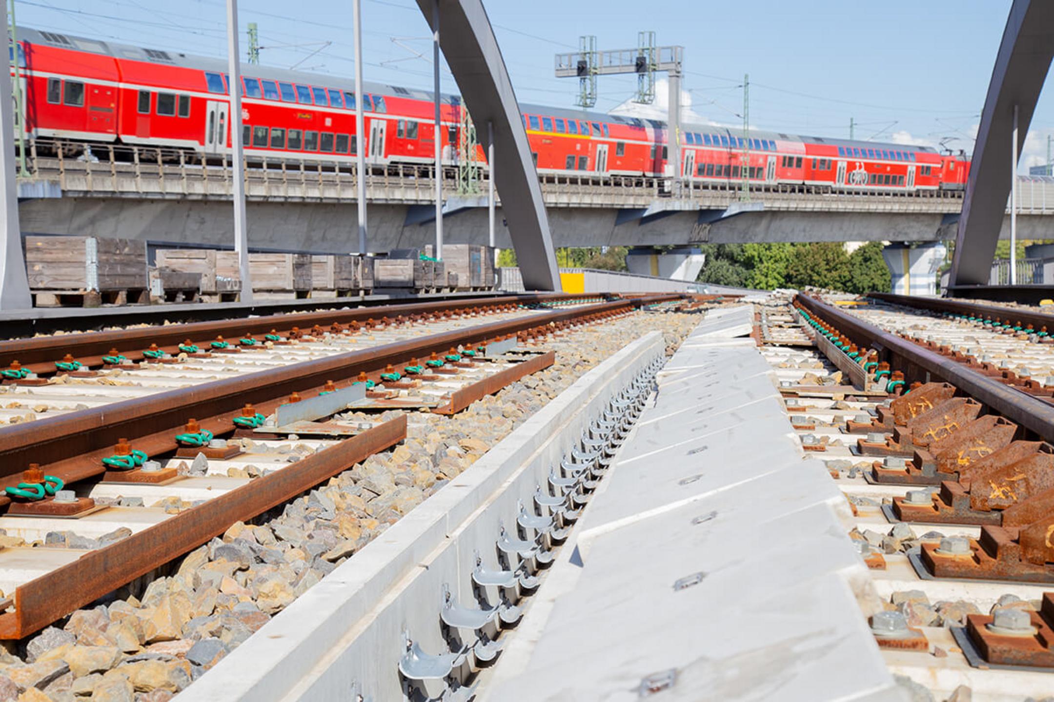 Bahngleise und die S-Bahn im Hintergrund bei Sonnenschein.